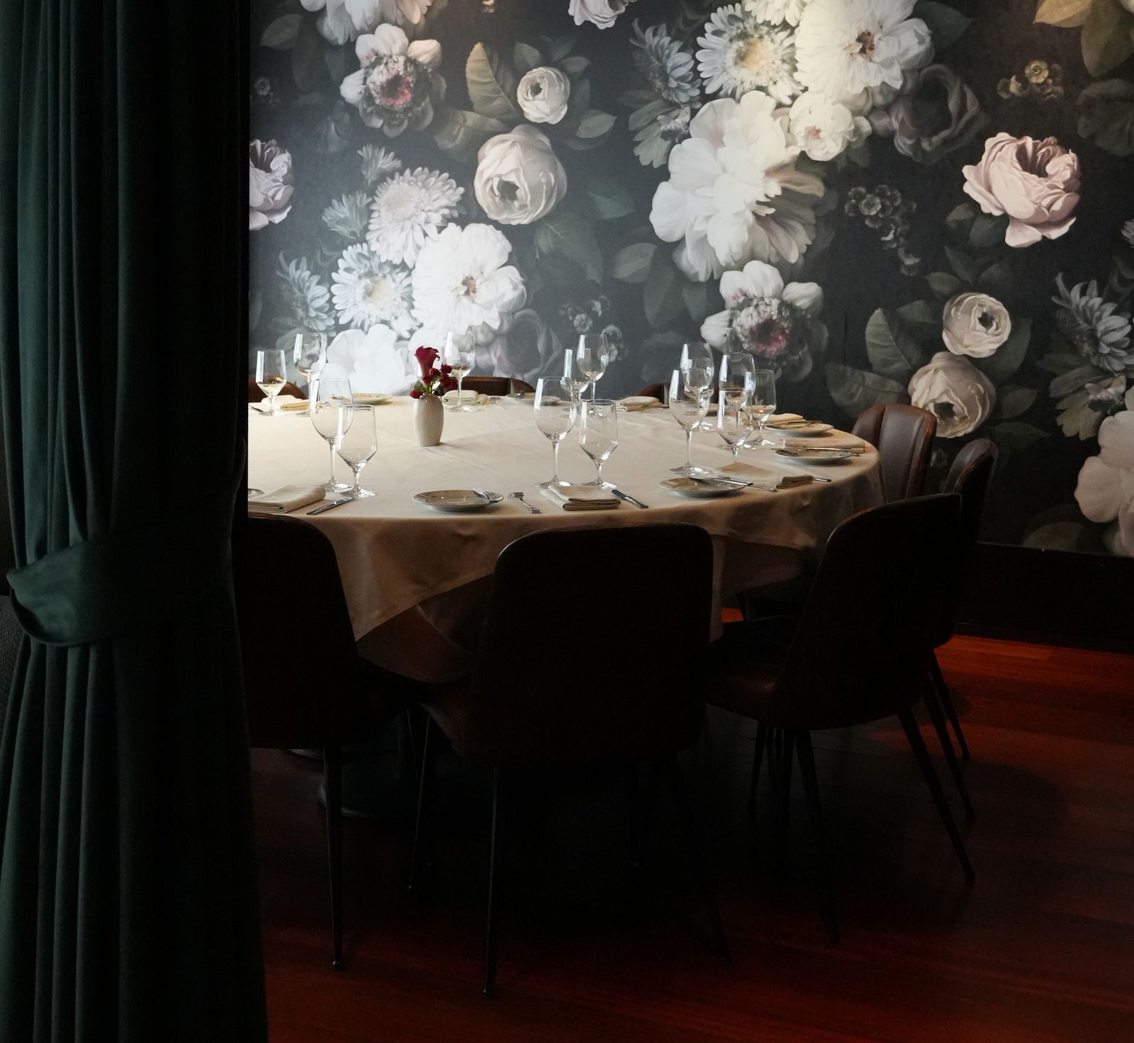 Private dining room with round set table against a dramatic dark floral mural
