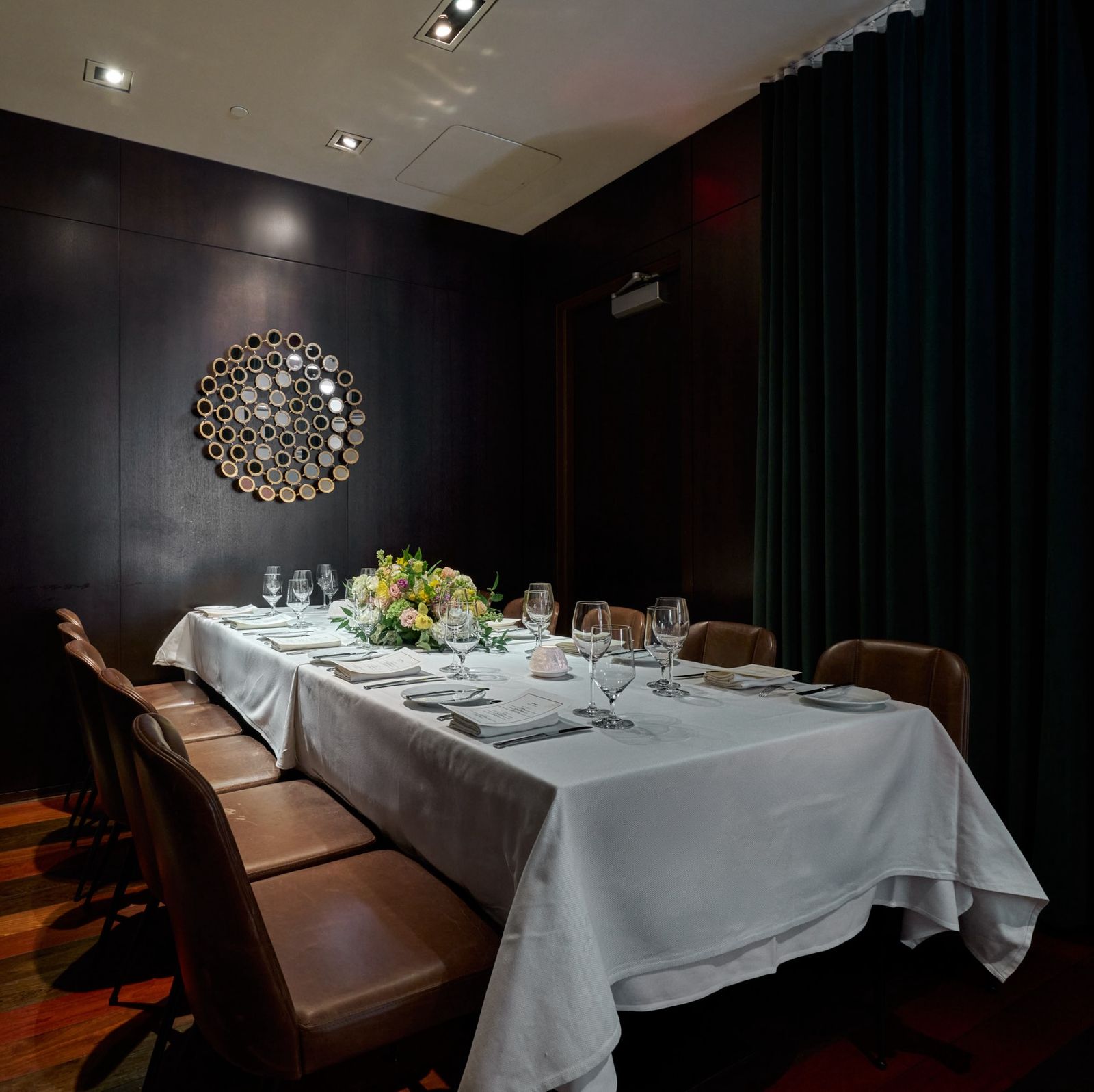 A long rectangular table set with a white table cloth and brown leather chairs