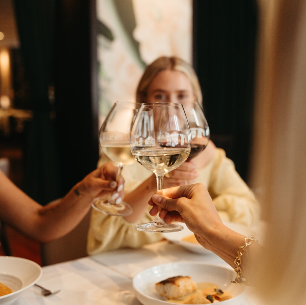 a group of people cheers-ing glasses of white wine