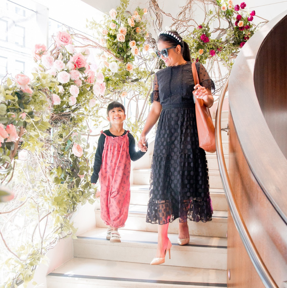 a mother and daughter hold hands and walk down a beautiful flower covered staircase