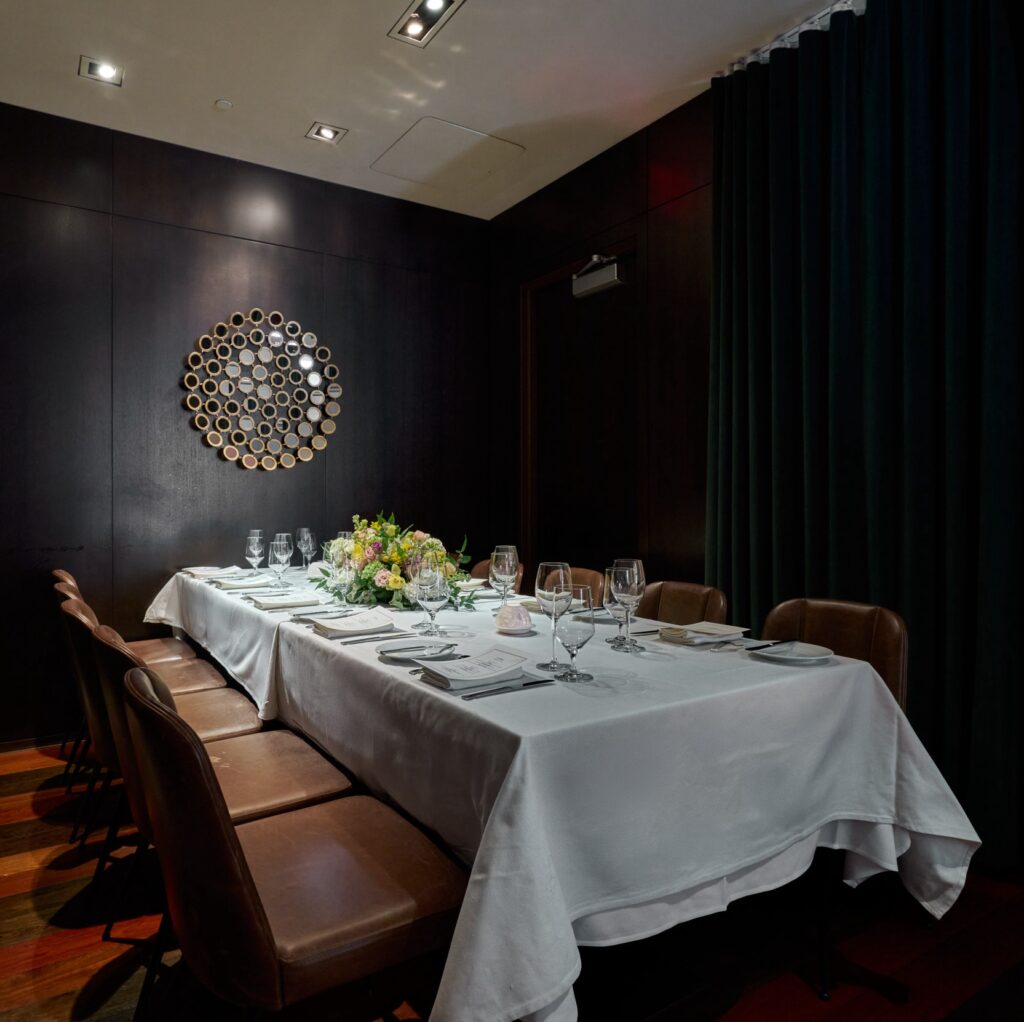 imperia private dining table at ai fiori - a long rectangular table set with a white table cloth and brown leather chairs