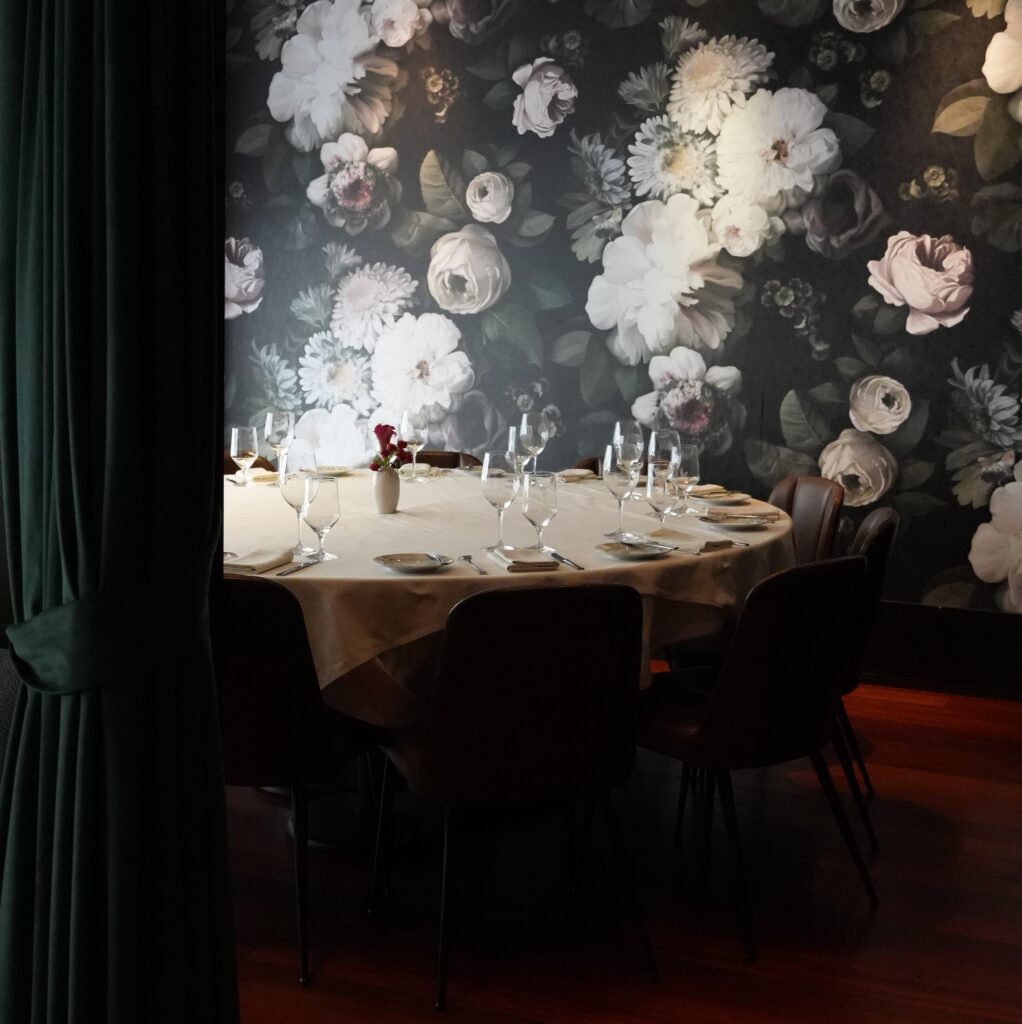 vernazza private dining room at ai fiori - floral wallpaper is seen behind a large round table