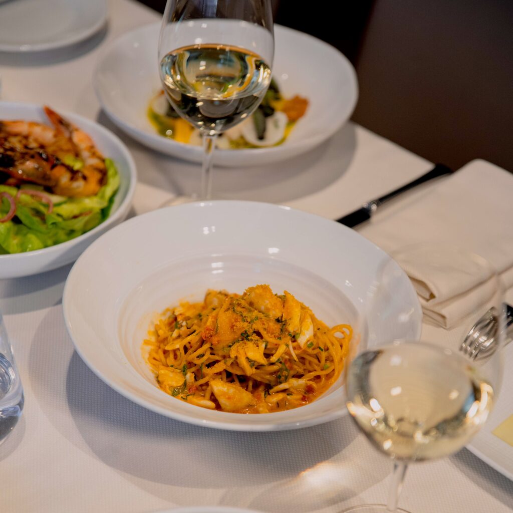 ai fiori's famous blue crab spaghetti on a table with many other dishes and glasses of wine, as part of the business lunch prix fixe